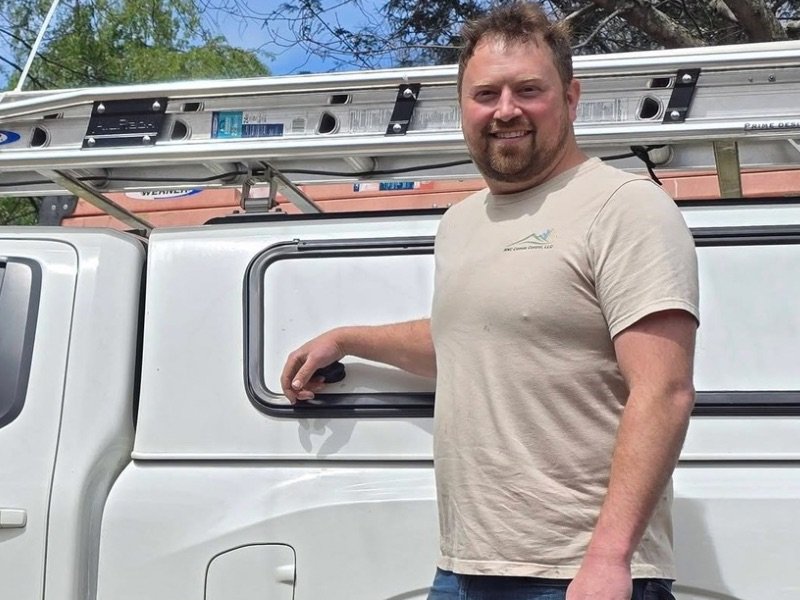 Chris Kuchar, HVAC installer at WNC Climate Control beside white work truck