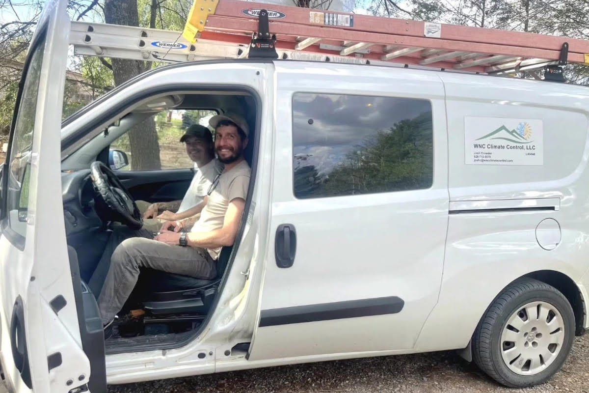 Two WNC Climate Control technicians smiling inside their white service van