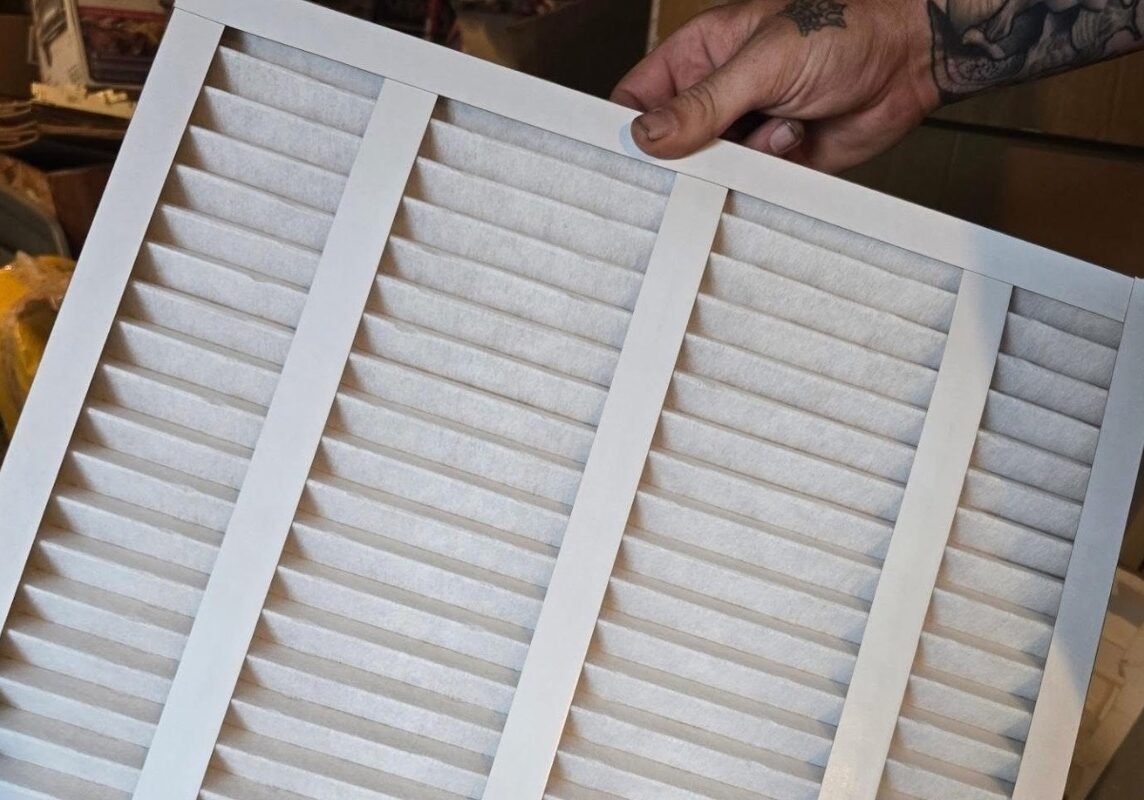 HVAC Technician holding a pleated air filter in a workshop