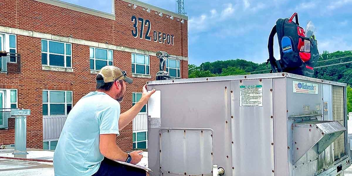 Technician servicing a rooftop unit on a commercial building